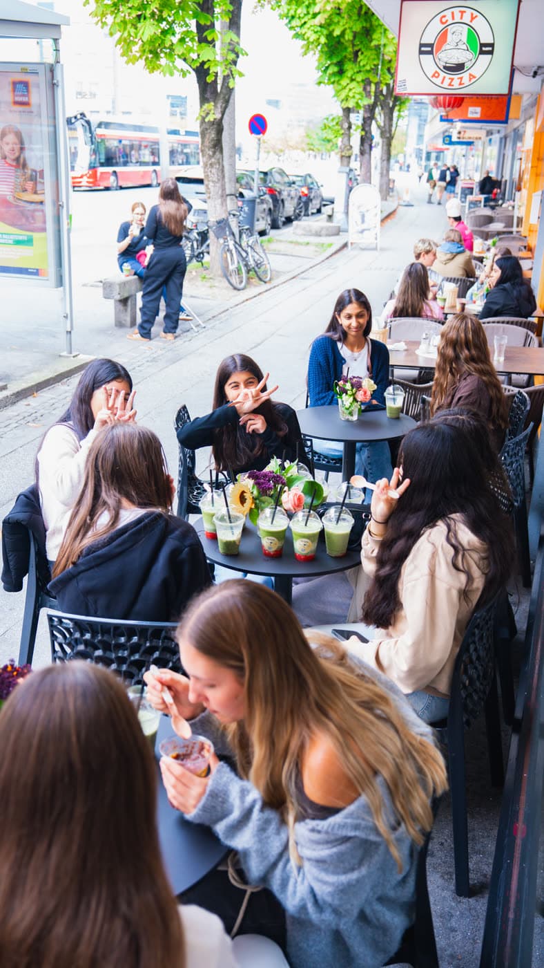 Gäste an den Tischen vor dem Lokal mit Matcha-Bechern